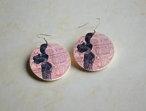 Two circular earrings with a design on a green surface.