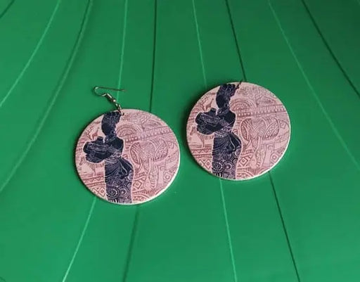 Two circular earrings with a design on a green surface.