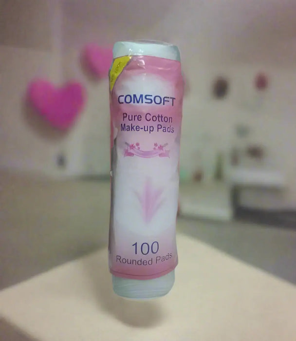 Comsoft pure cotton makeup pads packaging held by a hand on a tiled floor.