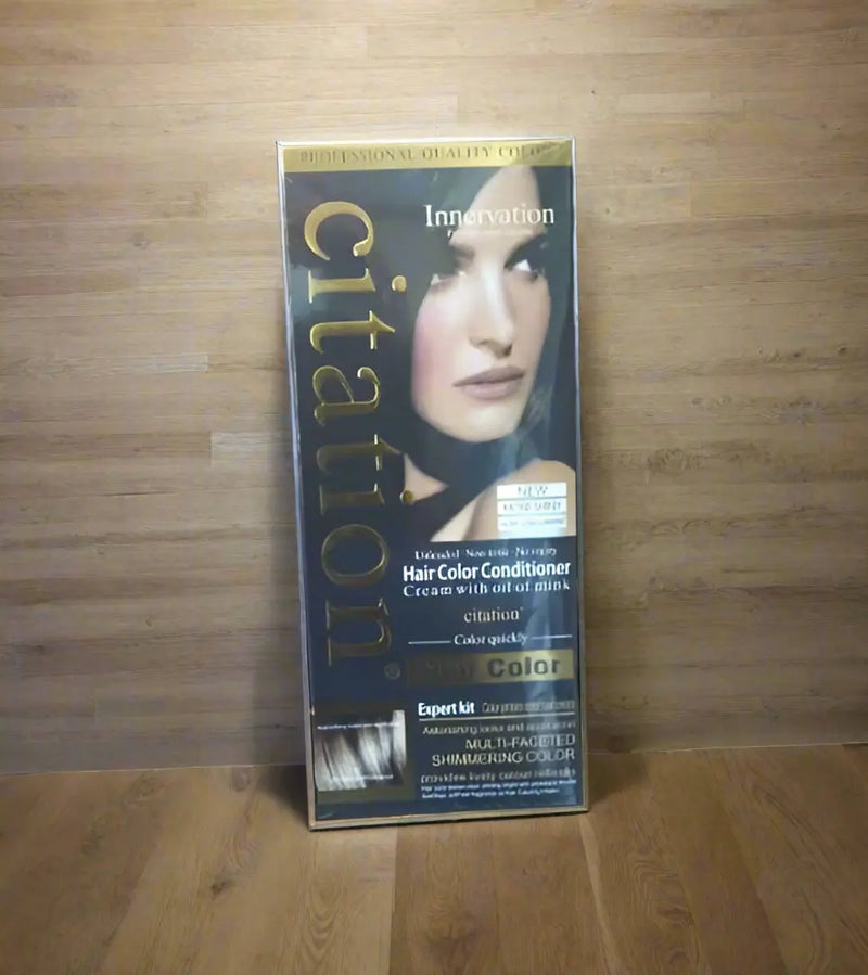 Hand holding a box of Citation hair color conditioner with a blurred background