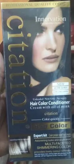 Hand holding a box of Citation hair color conditioner on a tiled floor.