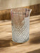 Clear glass vase with diamond pattern on a light-colored surface