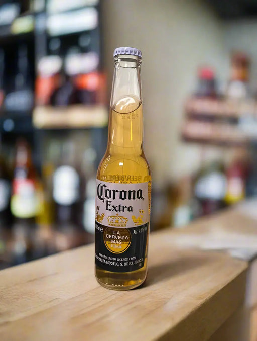 Hand holding a Corona Extra beer bottle on a tiled floor.