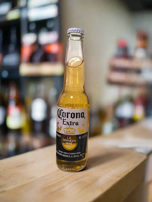 Hand holding a Corona Extra beer bottle on a tiled floor.
