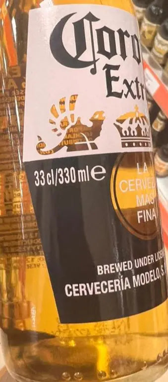 Hand holding a bottle of Corona Extra beer in a store setting