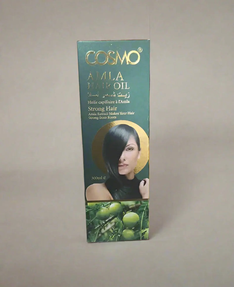 Cosmo Amla Hair Oil packaging held by a person in a store setting