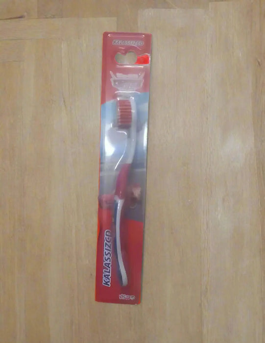 Hand holding a Colgate toothbrush package in a store setting