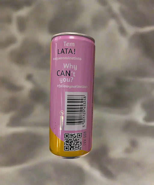 Purple can with text and a barcode held by a hand on a tiled floor.