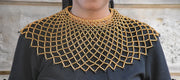 Black top with gold embroidered neckline against a neutral background