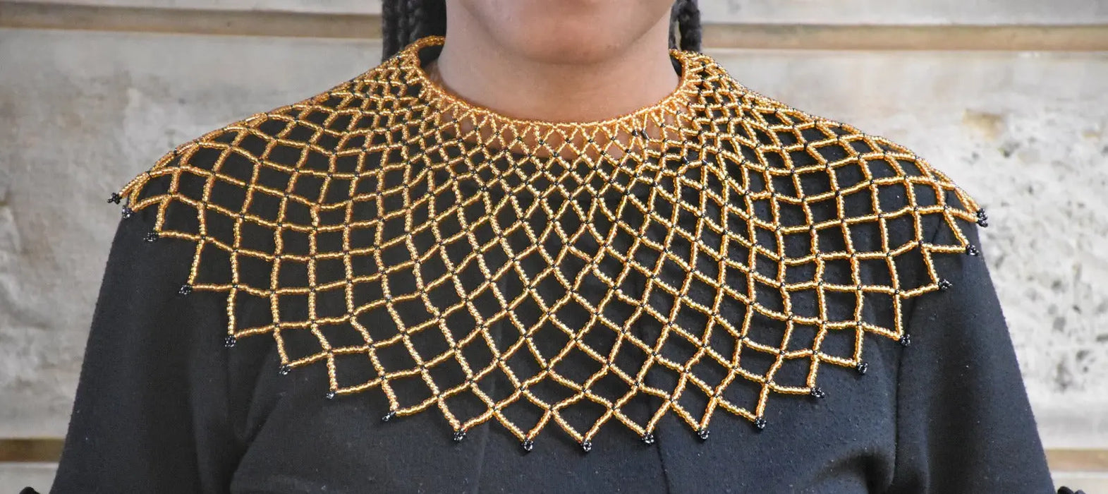 Black top with gold embroidered neckline against a neutral background