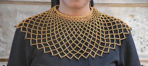 Black top with gold embroidered neckline against a neutral background