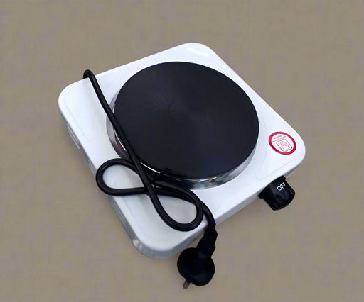 Small electric hot plate on a tiled floor with a hand holding it.