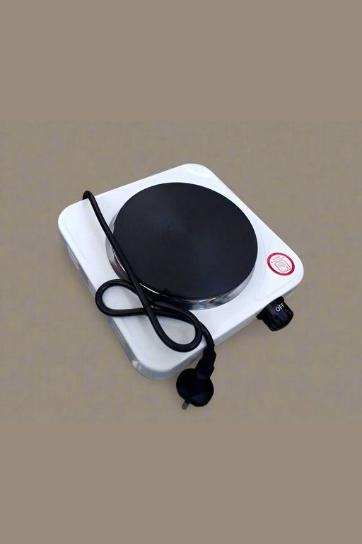 Small electric hot plate on a tiled floor with a hand holding it.