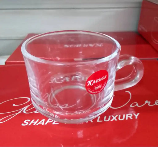 Clear glass mug with a red 'Karbon' label on a red surface