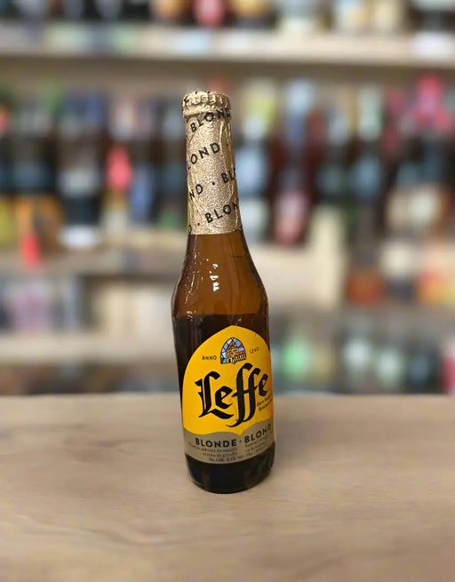 Leffe beer bottle held by a hand in a store setting