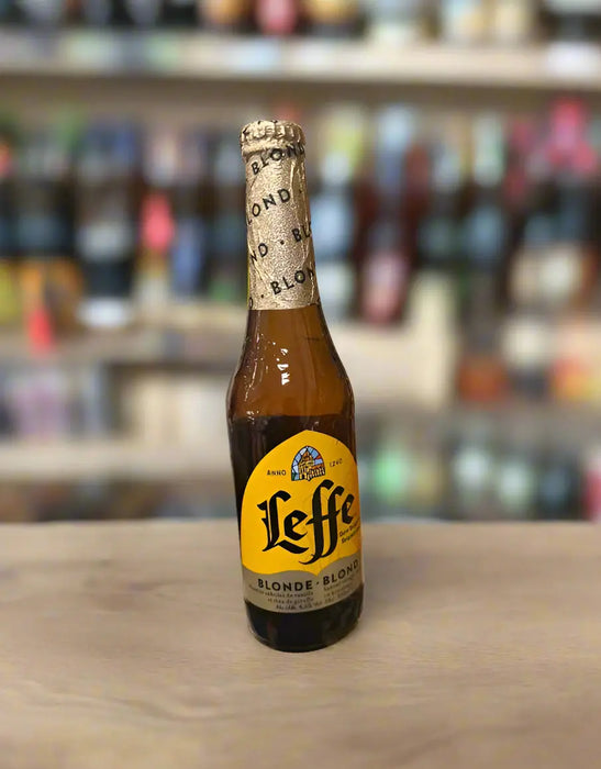 Leffe beer bottle held by a hand in a store setting