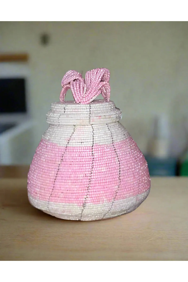 Hand holding a pink woven basket with a blurred background of colorful items.