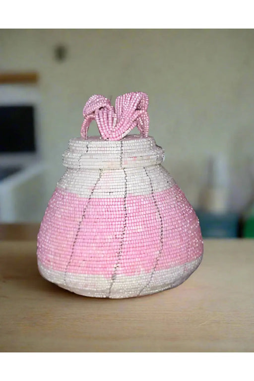 Hand holding a pink woven basket with a blurred background of colorful items.