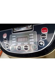 Black rice cooker with digital display and control panel on a wooden surface.