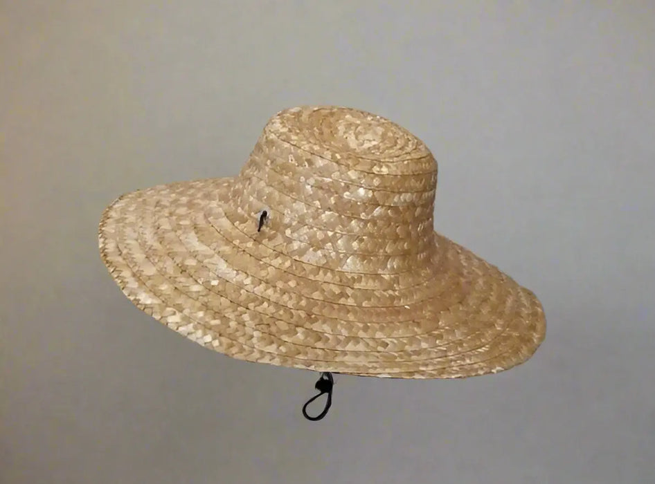Woven straw hat held by a person on a tiled floor.