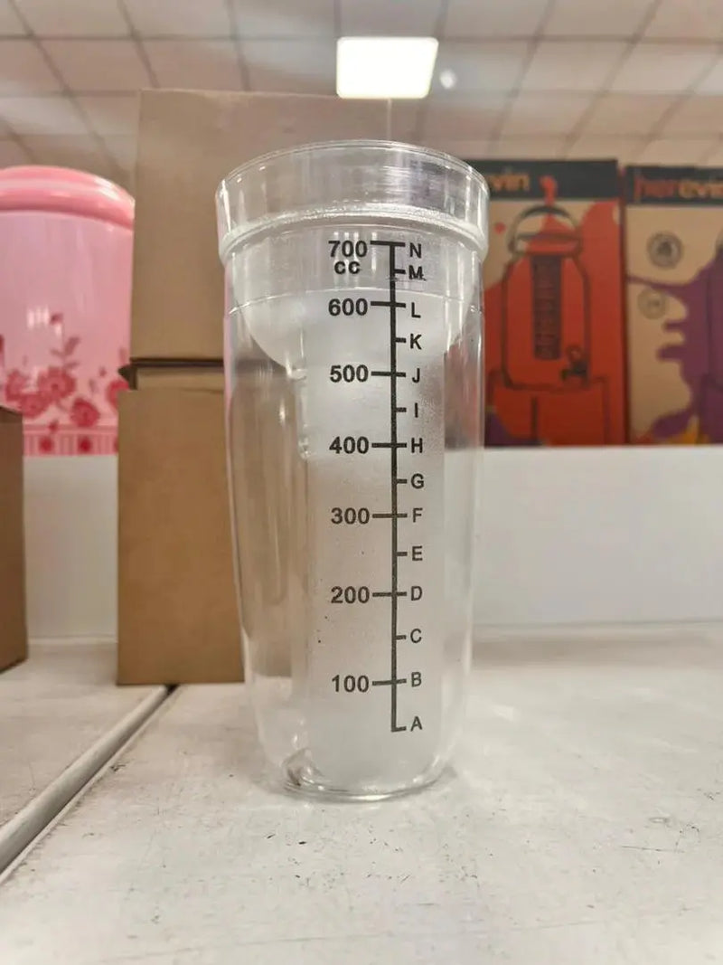 Clear measuring cup with liquid on a tiled floor