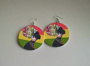 Pair of earrings on a green chair with a person's feet visible at the bottom.
