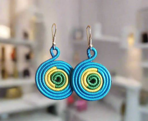 Colorful circular earrings held in a hand with a colorful background