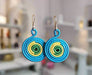 Colorful circular earrings held in a hand with a colorful background
