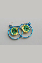 Colorful spiral earrings held in a hand with a background of more earrings on a board.