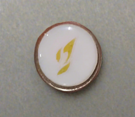 Round object with a white center and gold border held by a hand