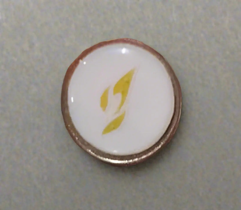 Round object with a white center and gold border held by a hand