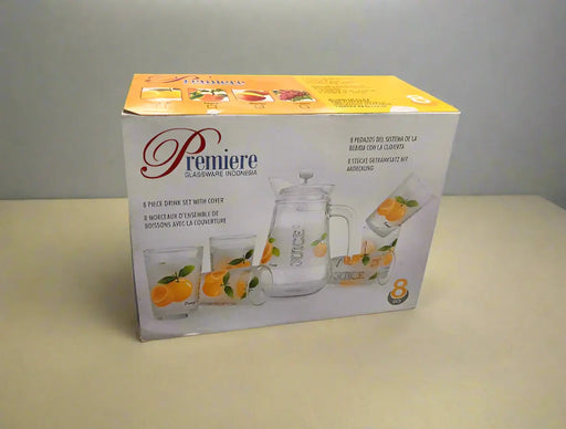 Box of 'Premiere' glassware set with orange-themed design on a tiled floor.