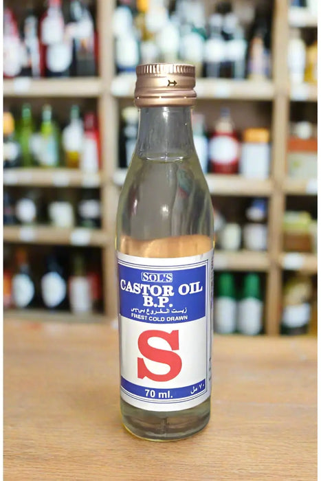 Hand holding a bottle of 'S' Castor Oil in a store setting