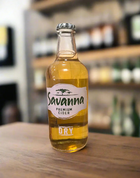 Savanna Premium Cider bottle held in a hand with a blurred store background