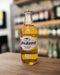 Savanna Premium Cider bottle held in a hand with a blurred store background