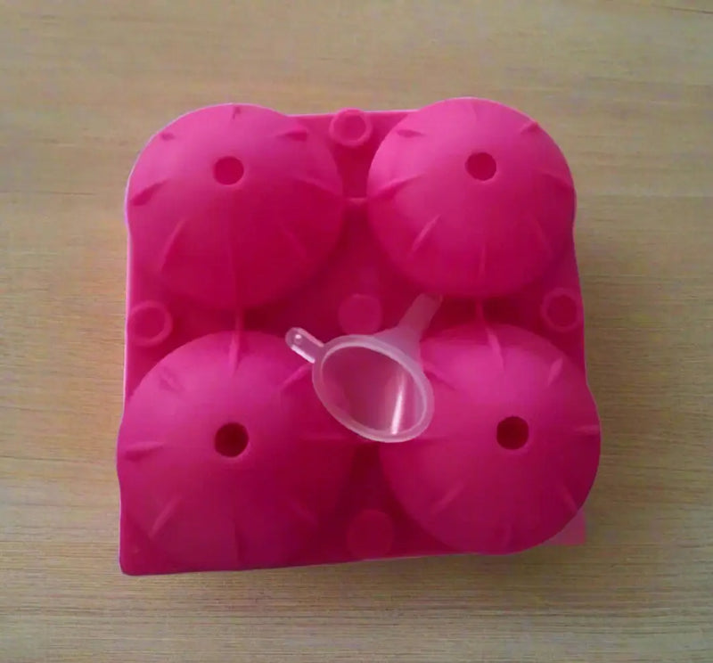 Pink silicone ice cube tray held by a hand on a tiled floor.