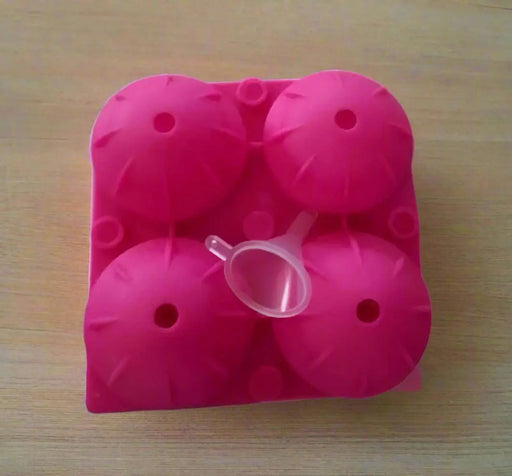 Pink silicone ice cube tray held by a hand on a tiled floor.