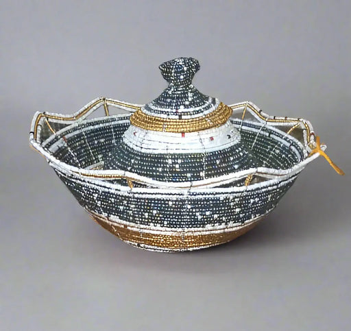 Hand holding a decorative bowl with intricate designs against a background of shelves with various items.