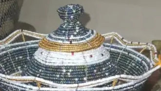 Hand holding a decorative bowl with intricate designs against a background of shelves with various items.