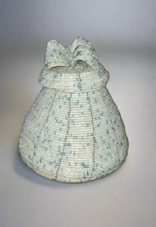 Handheld woven basket with a decorative lid against a background of ceramic pots.