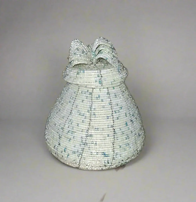 Handheld woven basket with a patterned lid against a blurred background