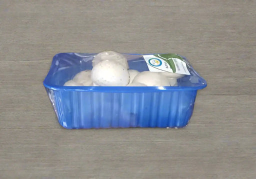 Hand holding a blue container with white balls and a green label.